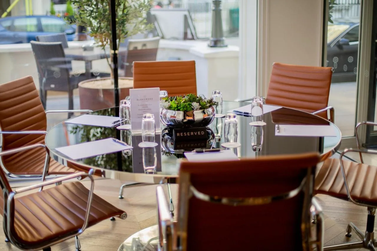 a glass table with chairs and a bowl of plants at Blakemore Hyde Park in London